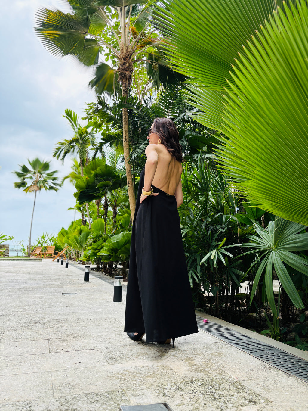 Back view of black halter maxi dress worn outdoors highlighting open halter design and flow