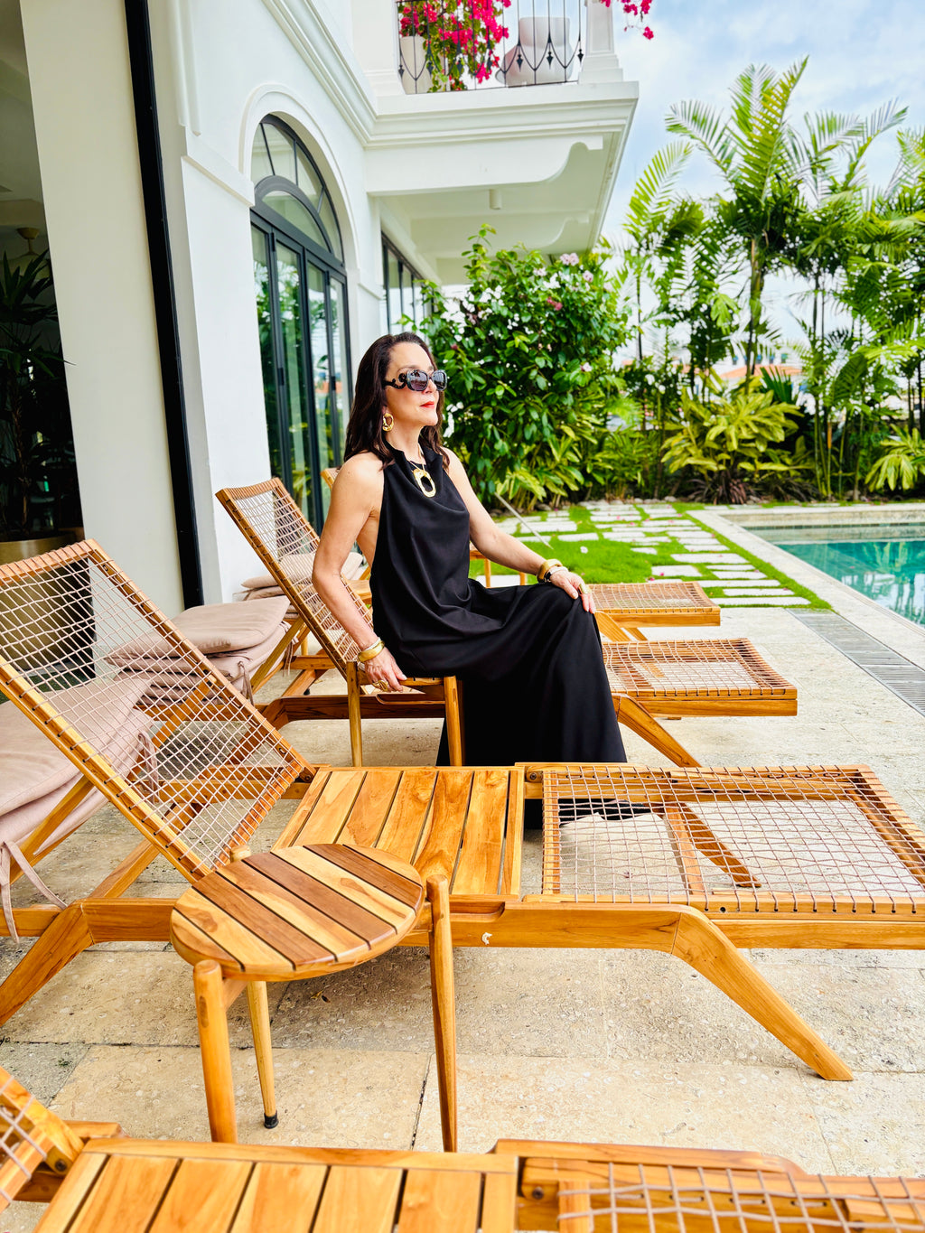 Black halter maxi dress styled in a luxury outdoor poolside setting with elegant resort vibe