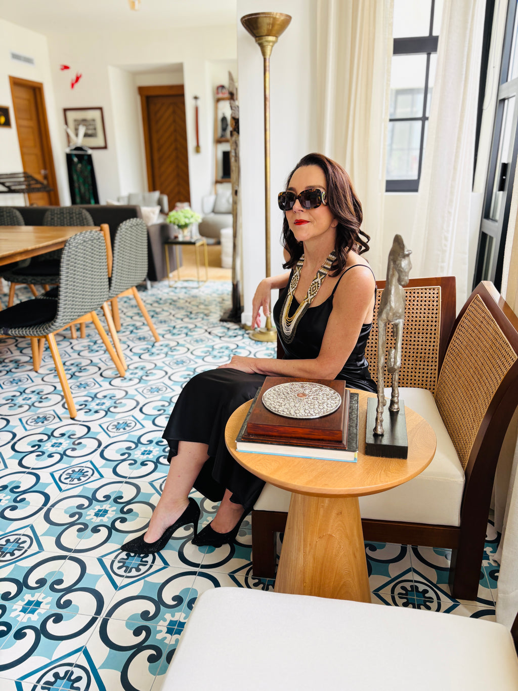 Black strappy maxi dress styled near window in natural light, elegant lifestyle setting