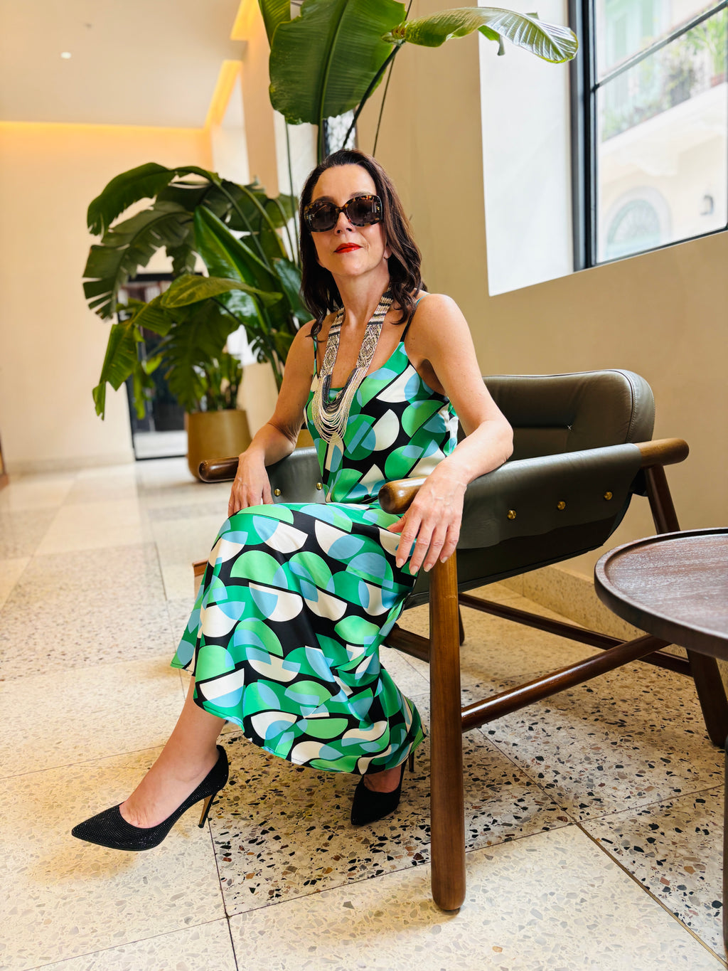 Elegant geo green strappy maxi dress worn in indoor setting highlighting artistic pattern and fit