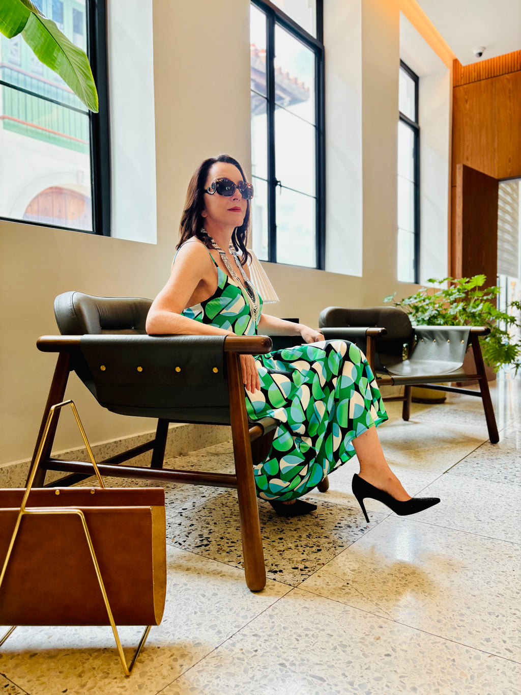 Geo green strappy maxi dress styled in a seated pose, showcasing relaxed luxury and elegance