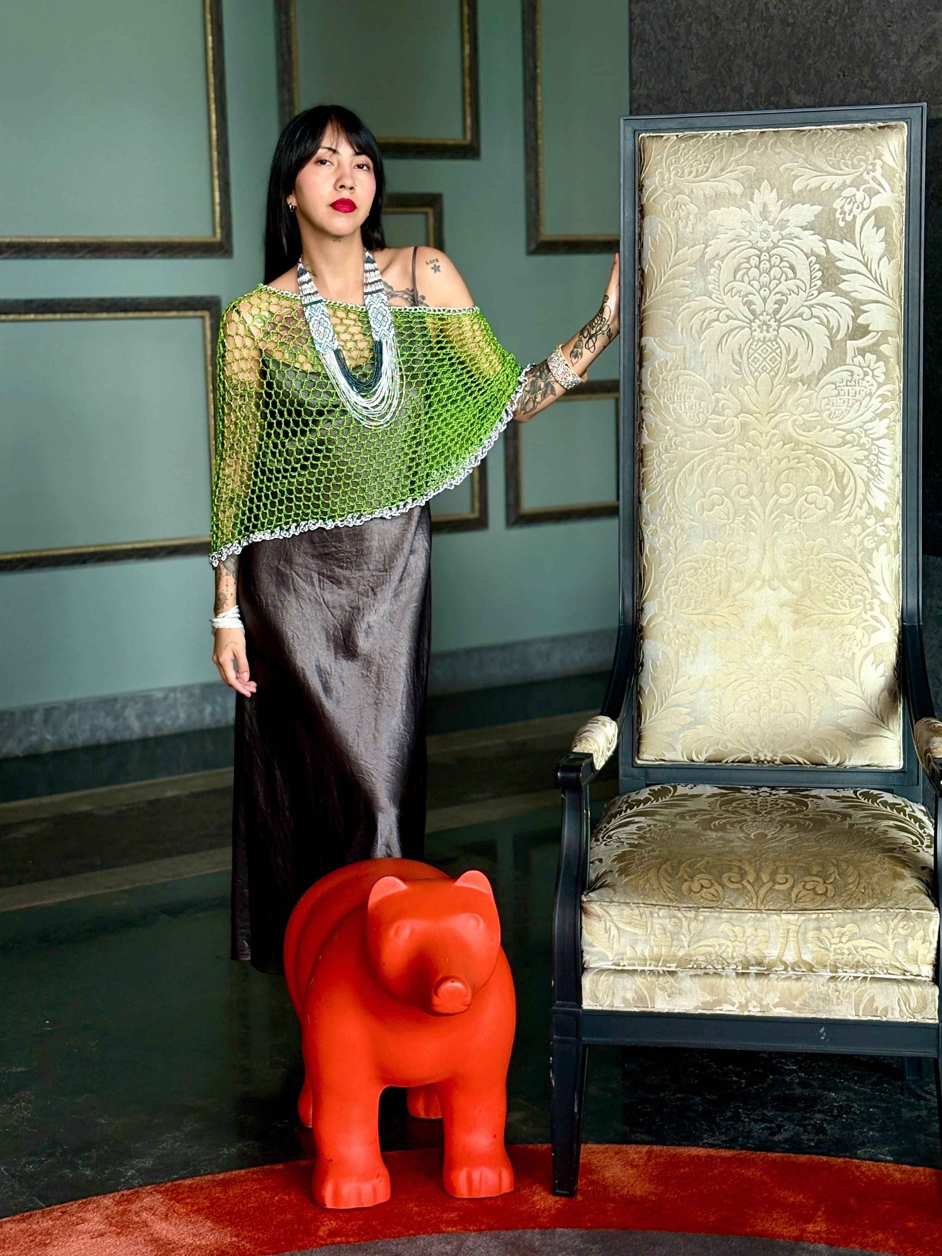 Model standing wearing green silver designer poncho
