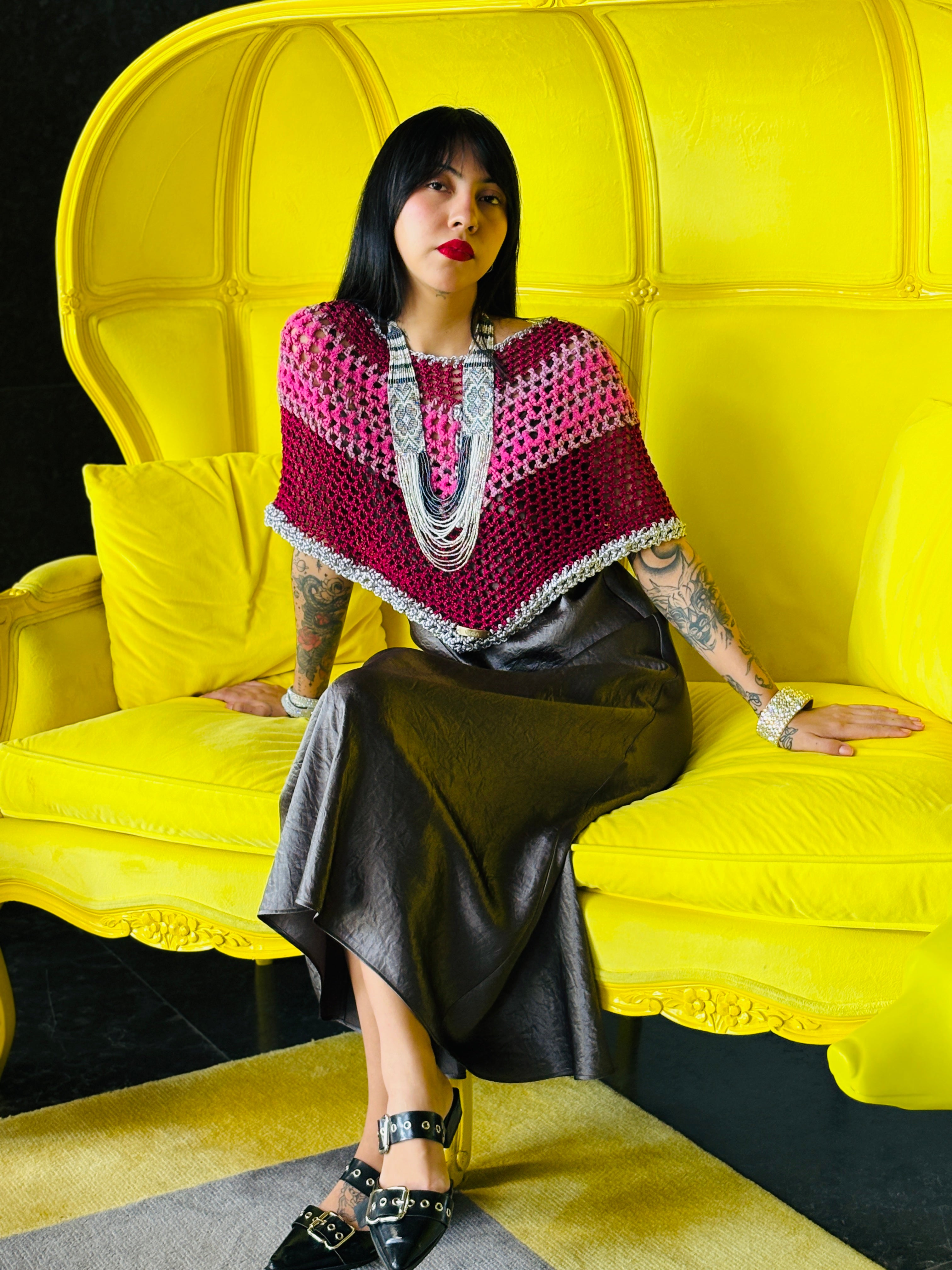 Elegant pink rainbow crochet poncho worn by model sitting