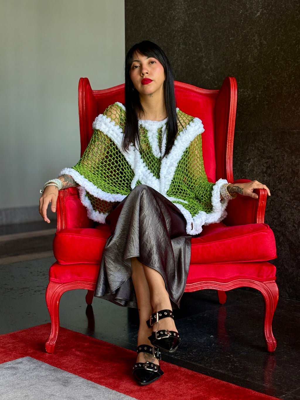 Handmade Santa Claus poncho styled on model sitting on red chair