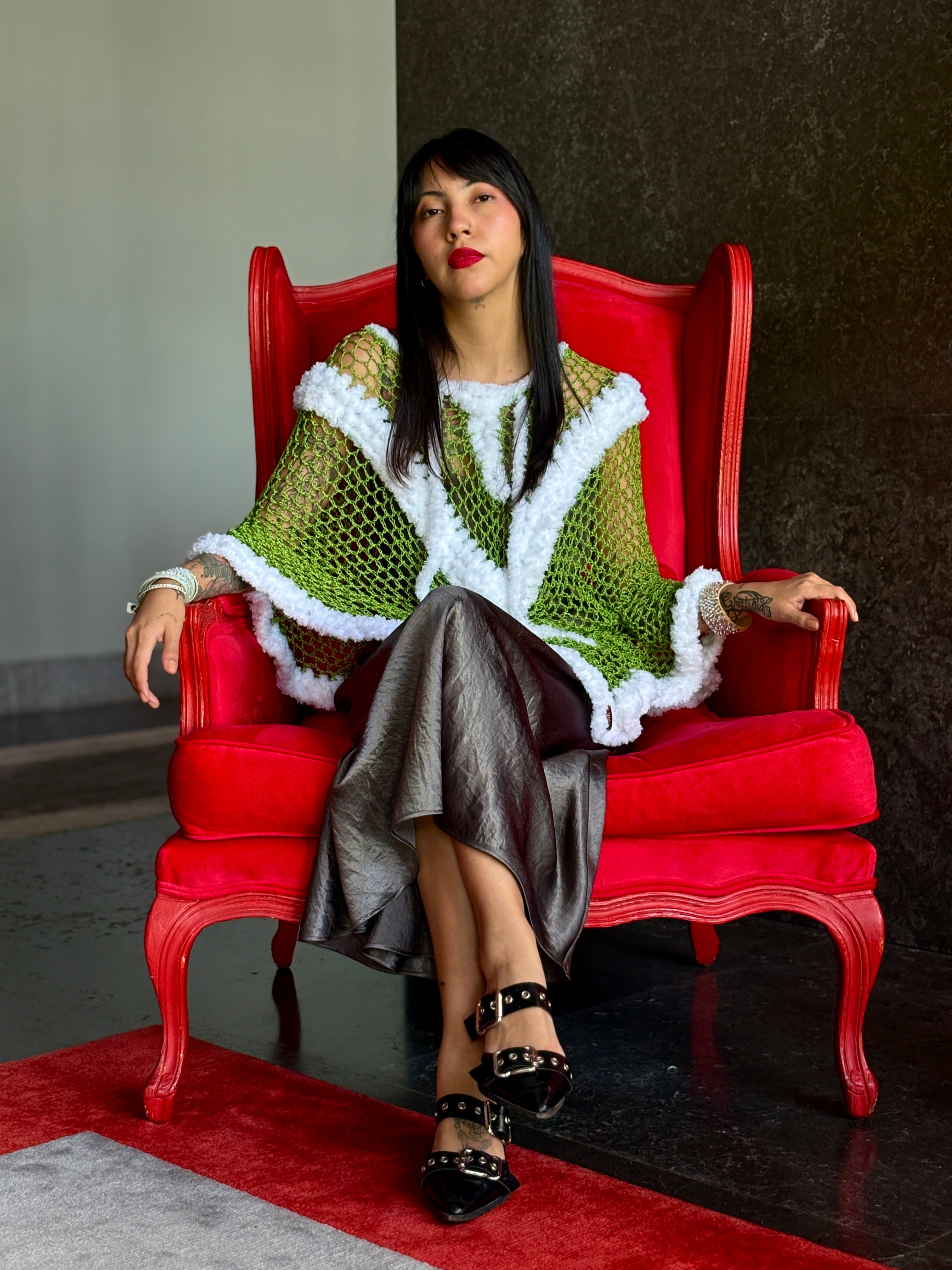 Handmade Santa Claus poncho styled on model sitting on red chair
