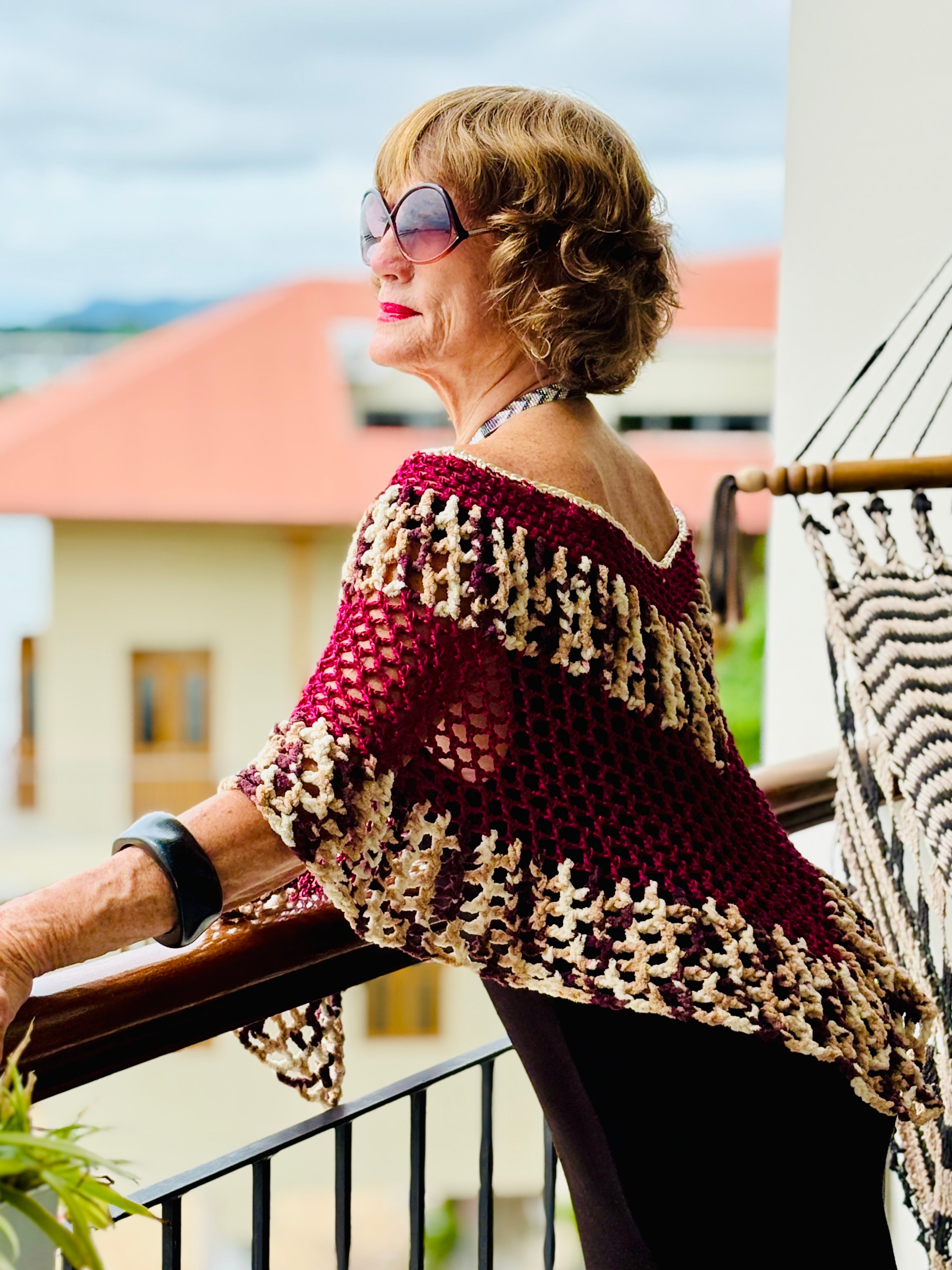 Model wearing tiger series bordeaux poncho standing on balcony