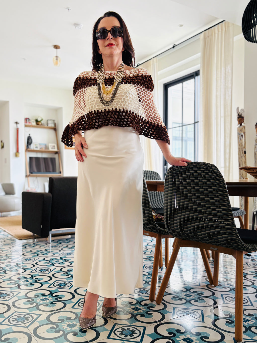 Full length view of brown and white velvet poncho paired with cream skirt and elegant accessories
