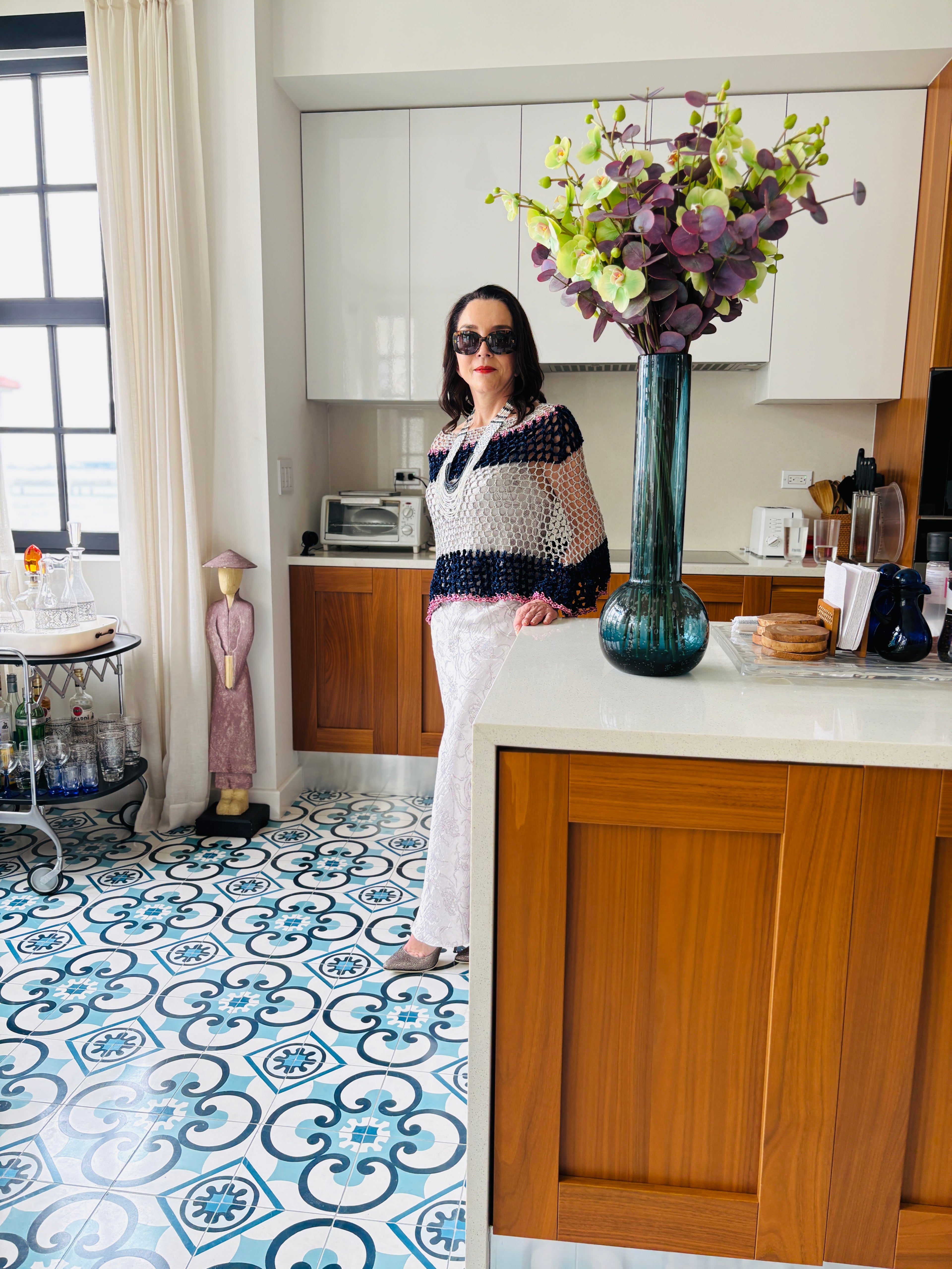 Side view of navy grey velvet poncho styled with statement jewelry in a luxury home setting